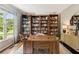 Cozy home office with custom built-in bookshelves, a large window, and a spacious desk at 7235 Compton Cir, Cumming, GA 30040