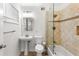 Bright bathroom featuring a pedestal sink, modern toilet, and shower-tub combo with glass partition and travertine tile surround at 115 Biscayne Nw Dr # F1, Atlanta, GA 30309