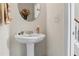Elegant powder room with a pedestal sink, oval mirror, and neutral color scheme at 2860 Cooper Brook Dr, Snellville, GA 30078