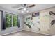 Light-filled bedroom with wood-look flooring, ceiling fan, large window with wooded view, and stylish accent wall at 47 Arbor End, Smyrna, GA 30080