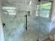 Glass shower featuring light marble tiling, a black showerhead, and a shower shelf at 1968 Rosewood Rd, Decatur, GA 30032
