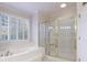 A full bathroom has a soaking tub beneath a window and a glass enclosed shower stall at 2883 Thurleston Ln, Duluth, GA 30097