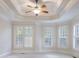 Bright bedroom with carpet, a tray ceiling, and many windows with natural light and ceiling fan at 2883 Thurleston Ln, Duluth, GA 30097
