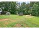 Large, grassy backyard featuring mature trees, a trampoline, and outdoor storage shed at 6223 Emerald Springs Se Dr, Acworth, GA 30102