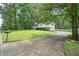 View of exterior and cracked driveway surrounded by mature trees and greenery with mailbox number at 6223 Emerald Springs Se Dr, Acworth, GA 30102