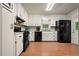 Classic kitchen with white cabinets, black appliances, and wood-look flooring at 6223 Emerald Springs Se Dr, Acworth, GA 30102