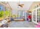 Bright sunroom with large windows, ceiling fan, stone floors and comfortable seating for relaxing at 380 Victorian Ln, Duluth, GA 30097
