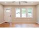 Bright living room featuring sleek hardwood floors, an exterior door, and a view of the front yard through large windows at 45 Driskell Ave, Mableton, GA 30126