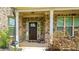 Inviting front porch with brick columns, a dark wood door, and manicured shrubs at 5381 Front Runner Ct, Sugar Hill, GA 30518