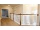 Upstairs hallway with hardwood flooring, a chandelier, and railing overlooking the staircase at 5381 Front Runner Ct, Sugar Hill, GA 30518