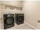 Modern laundry room featuring a black washer and dryer set and a storage shelf at 5381 Front Runner Ct, Sugar Hill, GA 30518