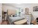 Comfortable bedroom featuring a tufted headboard, patterned bedding, bench, and decorative dresser with mirror at 3796 Village Crossing Ln, Ellenwood, GA 30294