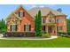 Elegant brick home featuring a stone facade, manicured lawn, and professionally landscaped front yard at 2832 Springbluff Ln, Buford, GA 30519