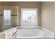 Corner soaking tub in bright bathroom features designer windows and tile accents at 1254 Hadaway Garden Nw Dr, Kennesaw, GA 30152