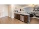 Open floor plan featuring kitchen island, wood floors, stainless dishwasher and cozy living room at 3350 Clawing Hawk Way, Douglasville, GA 30135