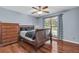 Cozy bedroom with wood floors, a large window, and a classic dark-wood dresser at 400 Little John Nw Dr, Lilburn, GA 30047
