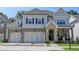 Charming two-story home featuring a stone and brick facade, three-car garage, and inviting front porch at 11255 Knollwood Bnd, Johns Creek, GA 30097