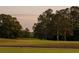 A scenic view of a lush golf course featuring mature trees and a golf cart on the fairway at 11255 Knollwood Bnd, Johns Creek, GA 30097