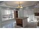 Bright kitchen with an island, white cabinets, a modern chandelier, and views of the wooded exterior at 110 Chippewa Ct, Riverdale, GA 30296