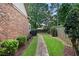 Backyard with brick house, wooden fence, neatly trimmed grass, brick path, and mature trees for a peaceful outdoor space at 1549 Lake Holcomb Ln, Marietta, GA 30062