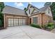 A brick and siding home featuring a spacious driveway and a large garage with green shrubbery and mature trees at 1549 Lake Holcomb Ln, Marietta, GA 30062