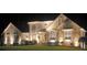 Beautiful two-story home with decorative stone accents, lush lawn, and elegant nighttime lighting at 6945 John Rivers Rd, Fairburn, GA 30213