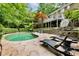 Backyard pool area with stone patio, lounge chairs, and a view of the home's deck at 910 Kings Arms Way, Johns Creek, GA 30022