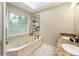 Bright bathroom featuring a large soaking tub, double vanity with granite counters and natural light from a skylight at 910 Kings Arms Way, Johns Creek, GA 30022