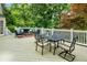 Outdoor deck with a dining set and lounge area, surrounded by a lush backyard and greenery at 910 Kings Arms Way, Johns Creek, GA 30022