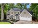 Elegant two-story home with a well-manicured lawn, a black roof and an attached garage at 910 Kings Arms Way, Johns Creek, GA 30022