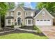 Charming two-story home with a manicured lawn, dark mulch flower beds, and stone walkway at 910 Kings Arms Way, Johns Creek, GA 30022
