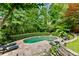 Secluded backyard pool with stone patio, lush greenery, and comfortable lounge chairs at 910 Kings Arms Way, Johns Creek, GA 30022