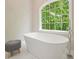 Modern white bathtub positioned next to a large, bright window with natural views at 3267 Standing Peachtree Trl, Kennesaw, GA 30152