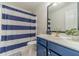 A bathroom offers a sink with gold faucet, white countertops, blue cabinets and a blue and white shower curtain at 2895 Dominion Walk Ln, Snellville, GA 30078