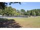 A community pool is surrounded by fencing and a large grassy space, trees and playground in background at 501 Bridlepath Ln, Peachtree City, GA 30269