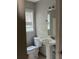 This bathroom features a white pedestal sink, toilet, and window with blinds at 1701 Charmeth Rd, Lithonia, GA 30058