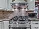 Close-up of a stainless steel range with decorative backsplash and cream cabinets at 4271 Edgewater Drive Northwest Nw Dr, Kennesaw, GA 30144