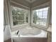 Bright bathroom featuring a corner tub, tiled surround, and natural light from large windows at 4715 Scotney Ct, Suwanee, GA 30024