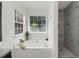 Bright main bathroom featuring a garden tub and tiled shower, bathed in natural light at 8690 Cedar Creek Rdg, Riverdale, GA 30274