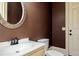 Cozy bathroom features dark brown walls, round mirror, and single vanity with toilet at 9695 Almaviva Dr, Alpharetta, GA 30022