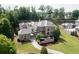 Expansive stone house with a winding driveway, lush lawn, and mature trees surrounding the property at 9695 Almaviva Dr, Alpharetta, GA 30022