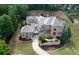 Expansive stone house with a winding driveway, lush lawn, and mature trees surrounding the property at 9695 Almaviva Dr, Alpharetta, GA 30022