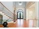 Grand foyer with a curved staircase, hardwood floors, and a decorative front door with sidelights at 9695 Almaviva Dr, Alpharetta, GA 30022