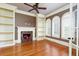 Cozy living room featuring a fireplace, built-in shelves, hardwood floors, and a ceiling fan at 9695 Almaviva Dr, Alpharetta, GA 30022