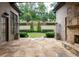 Beautiful stone patio leading to a manicured lawn with lovely landscaping and an outdoor stone fireplace at 9695 Almaviva Dr, Alpharetta, GA 30022