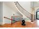 Elegant curved staircase featuring hardwood steps, ornate iron railing and natural light at 9695 Almaviva Dr, Alpharetta, GA 30022