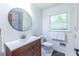 Bright bathroom featuring a modern vanity, round mirror, and a window with natural light at 1393 Sagewood Cir, Stone Mountain, GA 30083