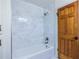 Bathroom with a shower and tub featuring new light gray tile and a wooden door at 1393 Sagewood Cir, Stone Mountain, GA 30083