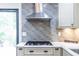 Close up of a gas cooktop stove with stylish vent hood and gray subway tile backsplash at 1393 Sagewood Cir, Stone Mountain, GA 30083