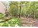 Backyard featuring a lush grassy area bordered by a wooded area with a tiered retaining wall at 5581 Fox Glove Ct, Douglasville, GA 30135